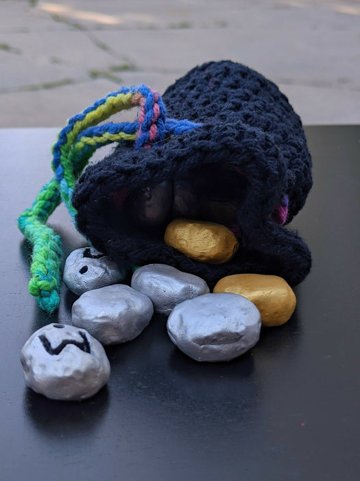 Photograph of the gold and silver stones spilling out of their matching bag.
