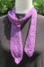 a narrow purple long scarf with an arrow-like motif wrapped around the neck of a dress form