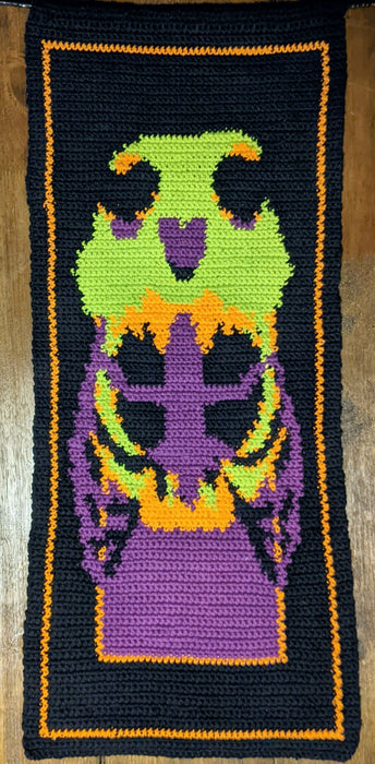 Photograph of the finished pattern sample. It features a green wolf skull with an open jaw surrounding a purple ribcage, all against a black background.
