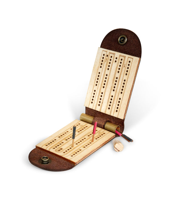 Folding leather travel cribbage board, open and unhinged, showing copper wire metal pegs in red and black finishes in peg holes, The pegs are made from electrical wire available at hardware stores. There is also an uncorked brass storage tube.