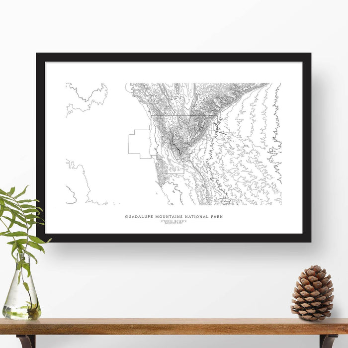 Map wall decor in a black frame. Contour lines of Guadalupe Mountains National Park are drawn on a white background. Text  below the map can be customized to create custom adventure art.