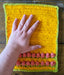 Photograph of the altar cloth with the creator's hand on it, for scale.