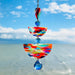 Paint Palette: Colorful handmade suncatcher with bold primary-toned polymer clay pieces in teardrop and arch shapes, paired with translucent blue faceted crystals and a rainbow chain.
