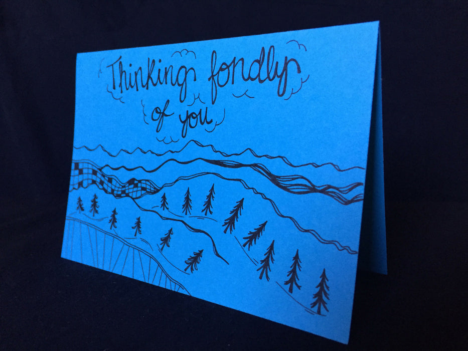 Card features abstract mountains and trees receding into a skyline that reads thinking fondly of you.