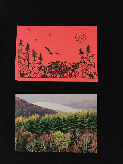 Card features evening nature scene with trees, fish, a seagull, and corner crabs on salmon-colored paper. Envelope features photograph of hills covered in trees during autumn.