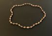Necklace made of spherical speckled stone beads, small round wooden beads, and white glass seed beads, in an alternating pattern.