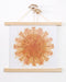 pear sunburst print in a poster frame consisting of wooden bars running along the top and bottom of the print. Two dried chive blossoms are sticking out of the top bar