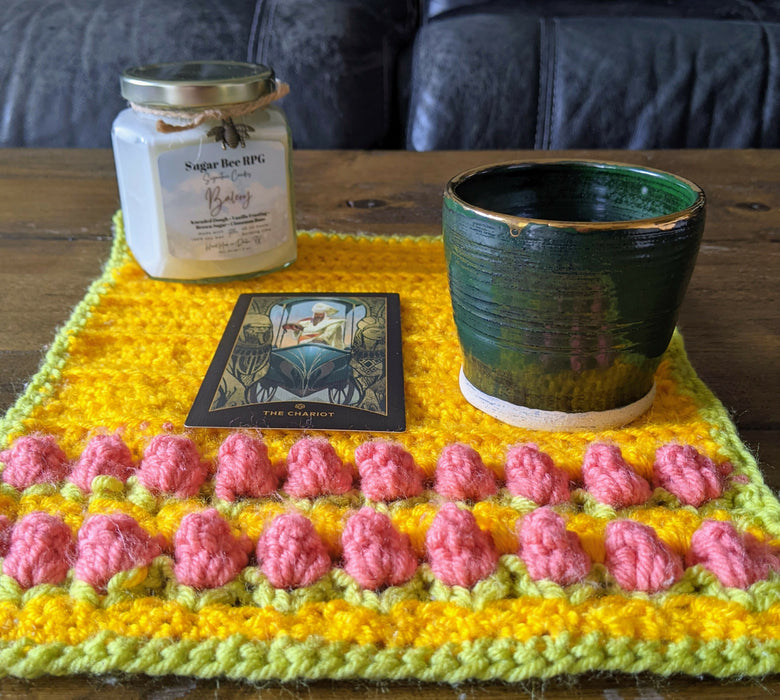 Photograph of the altar cloth with a candle, a small ceramic cup, and a tarot card on it.