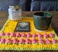 Photograph of the altar cloth with a candle, a small ceramic cup, and a tarot card on it.