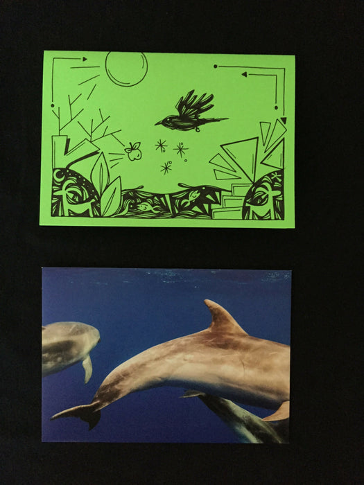 Card features abstract nature design including goats, fish, and a crow on lime green paper. Envelope features photograph of dolphins swimming in clear blue water.