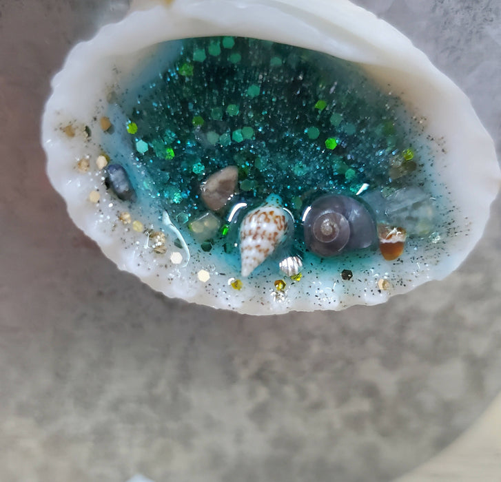 3 natural seashell magnets filled with resin to make ocean scenes.  They are bright pink, bright blue, and bright pink in color and have mini shells inside as decorations.