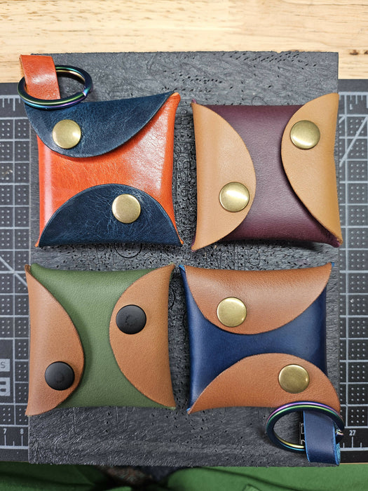 4 snap pouches arranged in a square pattern. Each pouch is roughly square, and both sides of the pouch wrap around to snap on the other side. Two of the pouches have loops that attach keyrings.