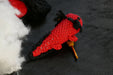 a red axolotl, viwed on it's back, on a black background with some coton tread, padding and a crochet as decors