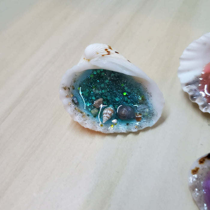 A close up of the bright blue resin ocean seashell magnet.