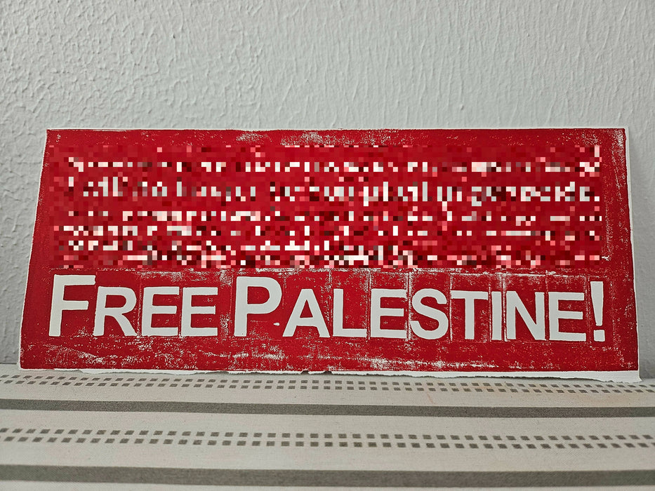 a pixelated image of a print in red ink with all but the words Free Palestine blurred out