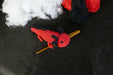 a red axolotl on a black background with some coton tread, padding and a crochet as decors