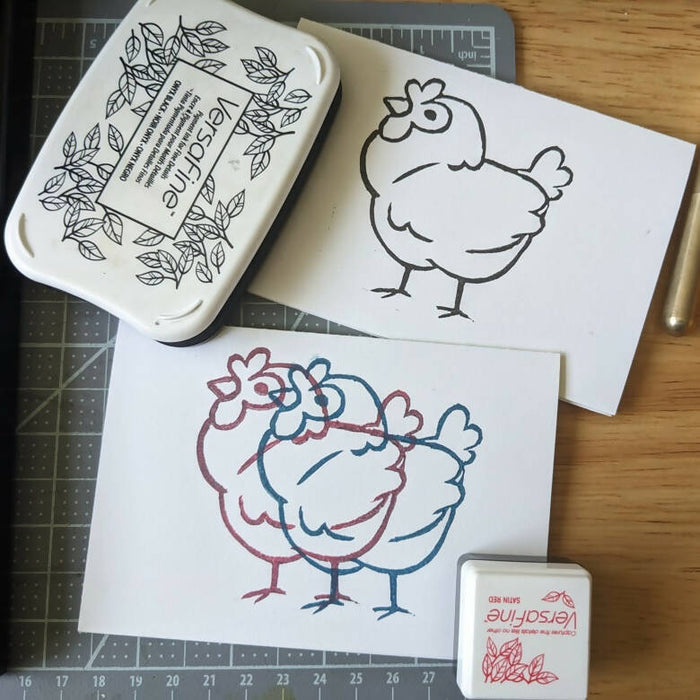 two greeting cards with a chicken design. One has a single print of the chicken design in black ink; the other has two overlapping prints in red and blue.