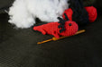 a red axolotl on a black background with some coton tread, padding and a crochet as decors